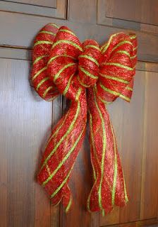 a red and green bow hanging on a door