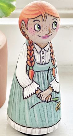 a ceramic figurine with an orange hair and green eyes wearing a blue dress