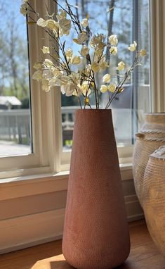 a vase filled with white flowers next to a window