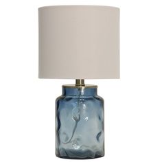 a blue glass table lamp with a white shade on the base and a light bulb