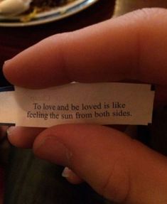 a person holding a piece of paper that says to love and be loved is like feeling the sun from both sides