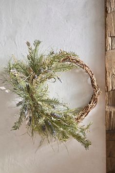 a wreath hanging on the wall next to a wooden door frame with greenery in it