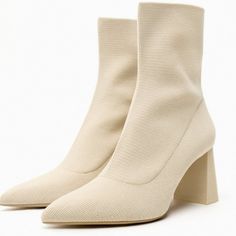 a pair of white high heeled boots on top of a white surface with no shoes