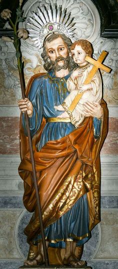 a statue of jesus holding a child with a cross on his arm and wearing a crown