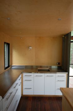 an empty kitchen with white cabinets and wood flooring is seen in this image from the inside