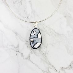 Discover the unique beauty of the 3/4" x 1-1/4" (20mm x 32mm) Calacatta Oval Pendant! This exquisite piece blends black, white and silver for a marbled look sure to turn heads. Includes an 18" sterling silver chain, but other chain lengths can be arranged. Oval Silver Necklace With Large Pendant, White Oval Pendant With Polished Finish, White Oval Pendant Necklace With Polished Finish, Nickel-free Oval Silver Necklace, Oval Nickel-free Silver Necklace, Silver Oval Pendant Jewelry, Modern Silver Necklace With Oval Pendant, Unique Black Oval Pendant Necklace, Silver Necklace With Oval Pendant