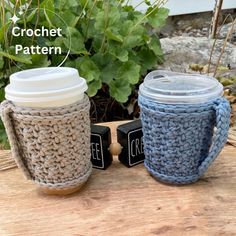 two crocheted coffee cups sitting next to each other on top of a wooden table