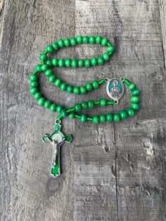 "This Green St Jude Rosary is crafted with Green Wooden beads, featuring an Italian made stunning green enamel centerpiece of Saint Jude. The centerpiece of this Catholic cord rosary is silver oxidized and \"Pray for Us\" is engraved on the back. The crucifix is die-cast for exceptional detail and features an inlaid St. Benedict medal front and back with a beautiful green enamel background.  Saint Jude Wooden Rosary Details: *8mm Green Wooden Beads *1 1/8\" St Jude Green Enamel Centerpiece  *1 3 Green Wooden Beads Jewelry For Gift, Green Wooden Beads Jewelry Gift, Green Vintage Jewelry With Wooden Beads, Green Rosary With 8mm Beads, Adjustable Green Rosary With Round Beads, Green Rosary With Round Beads As Gift, Handmade Green Rosary As A Gift, Green Beaded Rosary With Round Beads, Green 8mm Beads Spiritual Rosary