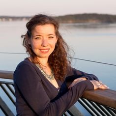 a woman is standing on the deck of a boat looking at the camera and smiling