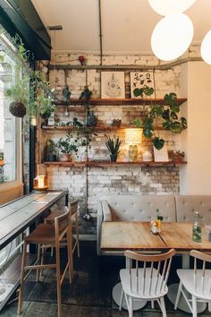 the interior of a restaurant with wooden tables, white chairs and shelves filled with potted plants