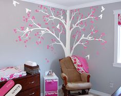 a baby's room decorated in pink and gray with a tree painted on the wall