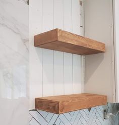 two wooden shelves on the side of a white wall with herringbone tile and wood trim