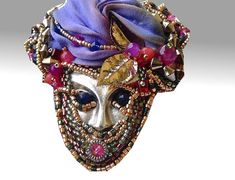 a metal mask with beads and flowers on it's head is shown in front of a white background