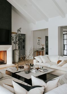 a living room filled with white furniture and a fire place in the middle of it