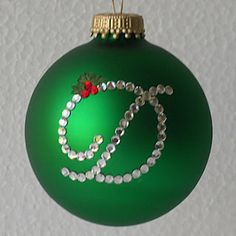 a green christmas ornament with beads and a red bow hanging from it's side