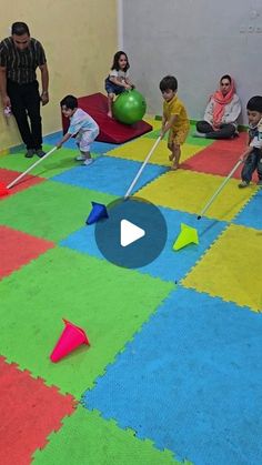 children playing with toys in an indoor play area while adults watch from the sidelines