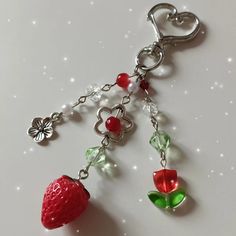 a strawberry key chain with charms hanging from it's side on a white surface