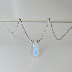 "Premium-quality, blue-flash moonstone gemstone necklace in sterling silver This elegant and minimalist-style necklace features a genuine, smooth-polished, blue flash moonstone teardrop-shaped gemstone (7 x 15 mm), wire wrapped in sterling silver and suspended on a dainty chain, finished with a lobster claw clasp.  Please note this is not a free-sliding stone.  In all its simplicity, this necklace is suitable for any occasion and for one of any age.  Moonstone is said to be associated with \"new beginnings\" and promotes inner growth and strength.  It is one of the birthstones for June. Please note your gemstone will be randomly selected from the same strand as the one shown in the photos, but owing to the unique nature of natural stones, each stone is slightly different in coloration and Minimalist Moonstone Pendant Crystal Necklace, Minimalist Moonstone Crystal Pendant Necklace, Handmade Minimalist Moonstone Necklace, Minimalist Sterling Silver Teardrop Pendant Necklace, Dainty White Moonstone Necklace, Minimalist Silver Teardrop Pendant Birthstone Necklace, Dainty Moonstone Teardrop Pendant Necklace, Minimalist White Gemstone Birthstone Necklace, Minimalist White Birthstone Necklace