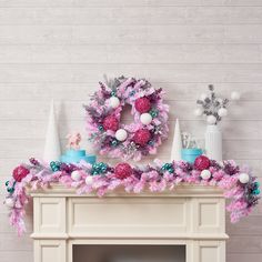 a fireplace decorated with pink and blue christmas wreaths on top of it's mantle