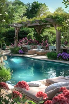 a pool surrounded by trees and flowers with lounge chairs next to the swimming pool area