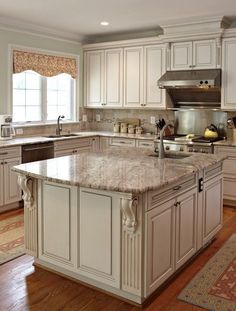 a large kitchen with white cabinets and marble counter tops, along with an island in the middle