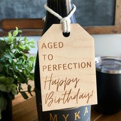 a bottle of wine with a tag that says aged to perfection happy birthday myka