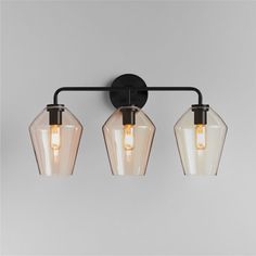 three lights are hanging on the wall in an industrial style bathroom fixture with black metal fixtures and clear glass shades