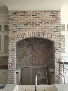 a kitchen with a sink and brick fireplace in the middle of it's remodel