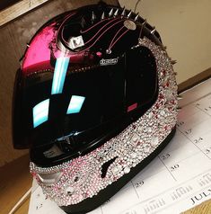 a motorcycle helmet with lots of jewels on the top and bottom, sitting on a table