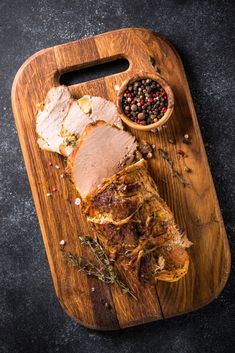 a wooden cutting board topped with meat next to a bowl of pepper and seasoning