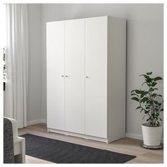 a white cabinet sitting next to a potted plant