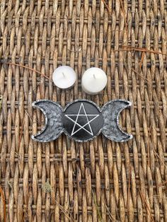 two candles sitting next to each other on top of a wicker table with angel wings