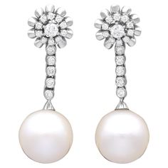 A stunning, fine and impressive pair of vintage south sea pearl, 1.30 carat diamond and 18 karat white gold earrings; part of our diverse pearl earring collections. These stunning, fine and impressive vintage pearl earrings have been crafted in 18k white gold. Each drop earring displays a stunning and large feature 14.18mm South Sea pearl terminal. The South Sea pearls suspend from an articulated linear drop composed of five individually collet set transitional modern brilliant round cut diamonds. The linear arrays are each suspended from an impressive cluster design, bearing eleven individually claw set transitional modern brilliant round cut diamonds, accented with a lobed gold border to the outer circumference. These South Sea pearl earrings with diamonds, for pierced ears, secure to th Vintage Pearl Jewelry, Vintage Pearl Earrings, Earring Displays, South Sea Pearls Earrings, Cluster Design, Transitional Modern, Pearl And Diamond Earrings, Vintage Pearl, Sea Pearl