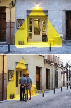 two people standing in front of a building with yellow paint on the outside and inside