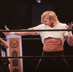 a man standing next to another man in a wrestling ring with his arms stretched out