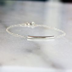 This sterling silver bracelet is the perfect minimal piece to wear alone or stack with other bracelets for an on-trend look. A subtly curved sterling silver tube glides freely across a sterling silver chain, finished with a silver spring ring clasp. Choose your ideal length from the drop-down menu. The length shown on the model is 7 inches. If you have an average size wrist, I would recommend either 6.5 or 7 inches. This piece can also be an anklet; measure your ankle for the best fit. Minimalist White Gold Bracelet With Silver Chain, Minimalist White Gold Silver Chain Bracelets, Minimalist White Gold Silver Chain Bracelet, Sterling Silver Bracelet With Delicate Chain For Everyday, Delicate Chain Sterling Silver Bracelet For Everyday, Everyday Sterling Silver Bracelet With Delicate Chain, Everyday White Gold Delicate Chain Bracelet, Simple Hypoallergenic Everyday Chain Bracelet, Simple Everyday Hypoallergenic Chain Bracelet