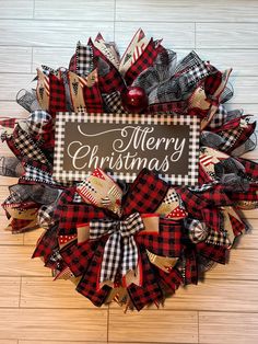 a christmas wreath with the words merry christmas on it and plaid fabric bows around it