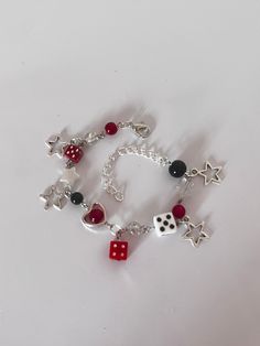 a red and white bracelet with dices, hearts, stars and beads on it