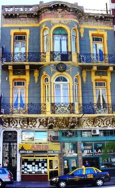 an old building with many windows and balconies on the top floor is painted yellow and blue