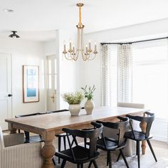 a dining room table with black chairs and a chandelier hanging from the ceiling