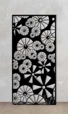 an abstract black and white artwork piece with geometric shapes in the middle, against a gray wall