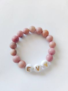 "*This is a single bracelet with pink stone beads and a custom word of your choosing. Letter beads have two colors: Gold and black. SIZING: 3.5\" PREEMIE/SMALL NEWBORN 4\"NEWBORN-5MONTH 4.5\" 6-12 MONTH 5\" 1 YEAR SIZING IS JUST A GUIDE. IT IS BEST TO MEASURE FOR BEST ACCURACY. Take a sting and loop it around your babies wrist, leave a bit of wiggle room and measure to a tape measure or ruler. *Handmade item *Can be personalized Stretch and elastic fit. Customizable worded bracelet stacks. Perfe Hypoallergenic Pink Bracelets For Everyday, Spiritual Pink Jewelry For Birthday, Adjustable Pink Name Bracelet, Adjustable Round Pink Name Bracelet, Pink Hypoallergenic Name Bracelet For Everyday, Pink Round Beads Bracelets For Birthday, Pink Beaded Bracelets For Birthday, Custom Name Pink Stretch Bracelet, Everyday Pink Hypoallergenic Stretch Bracelet