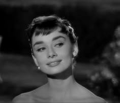 an old black and white photo of a woman with short hair in a strapless dress