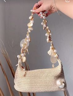 a hand holding a purse with shells and pearls