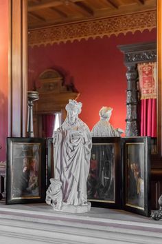 three framed pictures are sitting on the mantle in front of a statue and other items