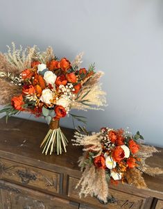 two bouquets of flowers sitting on top of a wooden dresser next to each other