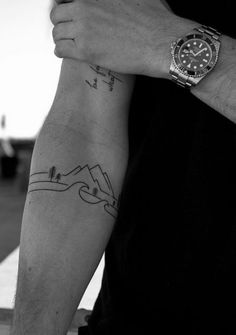 a man with a watch on his arm holding onto another person's arm while they both have tattoos on their arms