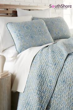 a bed with blue and white bedspread, pillows and pillow cases on it