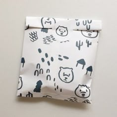 a folded piece of paper with an image of bears and cactuses on it, sitting on top of a white surface