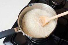 a wooden spoon stirring rice in a pot on the stove